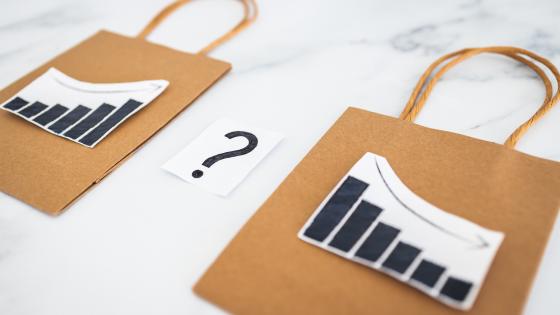 Two paper shopping bags with charts showing inflation going up and down